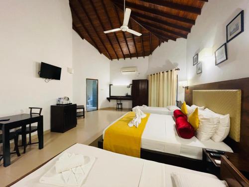 a bedroom with two beds and a desk and a television at Hotel Kamrel Sigiriya in Sigiriya