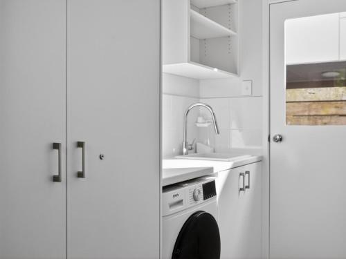a kitchen with white cabinets and a sink at The Pink Door, Absolute Beachfront House in Scarborough