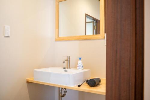 a bathroom with a white sink and a mirror at Umibe no yado yo-riyo-ri in Amami