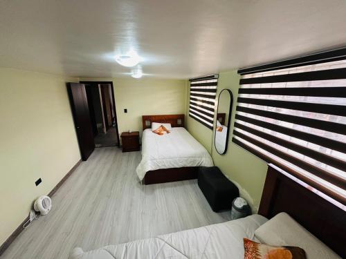a small bedroom with two beds and a window at BaseCotopaxi Mini depart 5p free parking in Latacunga