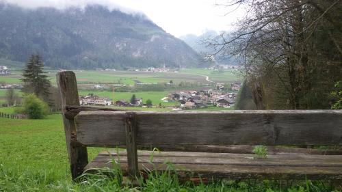 a wooden bench in a field with a view of a town at Lahnerhof in Campo Tures