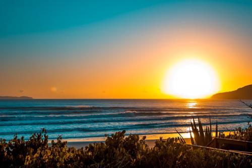 a sunset on the beach with the ocean at Marin Château Empreendimentos Turísticos in Bombinhas