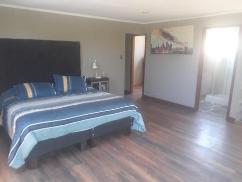 a bedroom with a bed with blue sheets and a wooden floor at la casa del cerro in Casas de Batuco