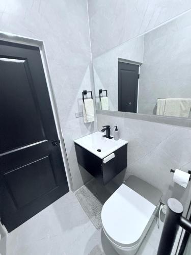 a white bathroom with a toilet and a sink at Modern Caribbean retreat 2 in Kingston