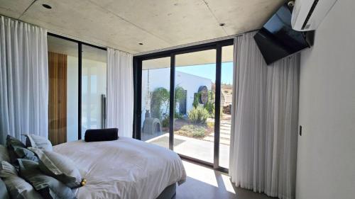 a bedroom with a bed and a large glass window at Walvishaai in Stompneusbaai