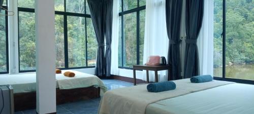 two beds in a room with large windows at water fall resort soksan in Phumĭ Kaôh Rŏng