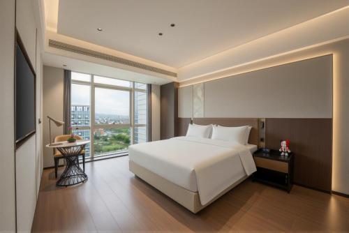 a bedroom with a white bed and a large window at 义乌雅寓酒店国际商贸城六区店 in Yiwu