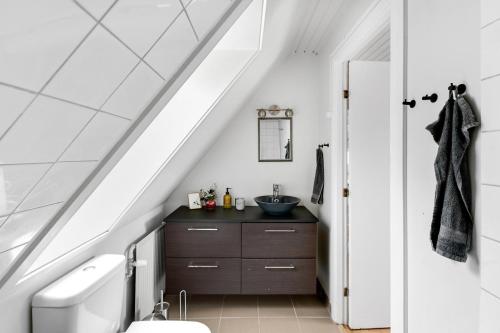 a bathroom with a sink and a toilet under the stairs at Holiday Apartment On Bornholm With Sea View in Svaneke