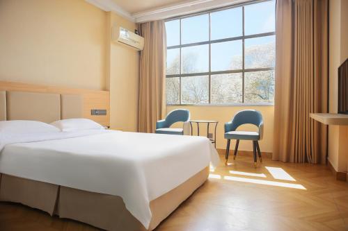 a hotel room with a bed and a table and chairs at Shenzhen Green Oasis Hotel, Baoan in Bao'an