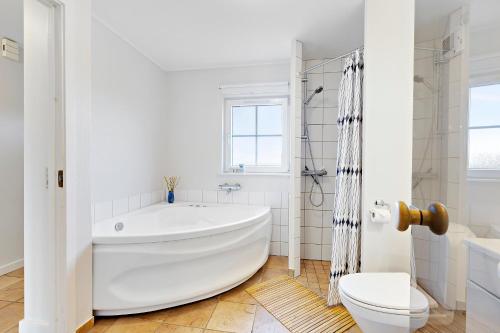 a white bathroom with a tub and a toilet at Charming Terraced House By The Beach And Forest in Bro