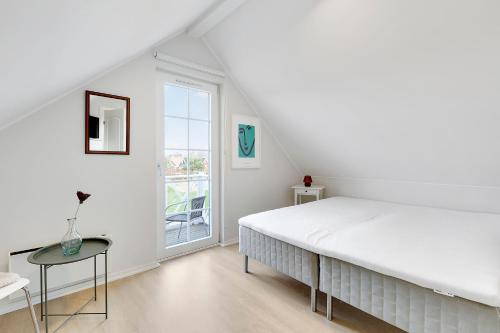 a white bedroom with a large bed and a table at Charming Terraced House By The Beach And Forest in Bro