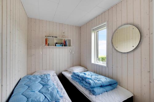 zwei Betten in einem Zimmer mit Spiegel und Fenster in der Unterkunft Neu Restauriertes Sommerhaus Mit Meerblick in Aabenraa