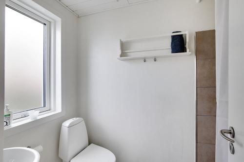 ein Badezimmer mit Toilette, Waschbecken und Fenster in der Unterkunft Neu Restauriertes Sommerhaus Mit Meerblick in Aabenraa