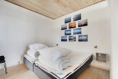 Ein Schlafzimmer mit einem Bett mit weißen Laken und Bildern an der Wand in der Unterkunft Exklusive Lage Direkt Am Wasser in Kolding