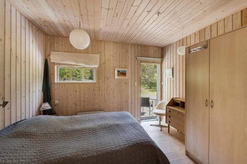 a bedroom with a bed and a wooden ceiling at Lovely Cottage In Recreation Area in Åkirkeby