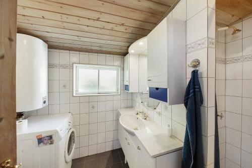 a bathroom with a sink and a washing machine at Lovely Cottage In Recreation Area in Åkirkeby