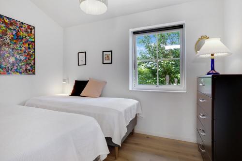 a white bedroom with two beds and a window at New And Cozy House By The Beach And Forest in Hornbæk
