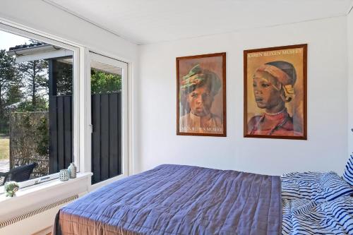 a bedroom with two pictures hanging on the wall at Lovely Cottage Full Of Holiday Atmosphere in Rødby