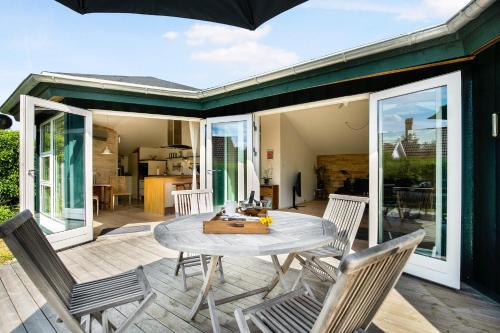 eine Terrasse mit Tisch und Stühlen auf einem Deck in der Unterkunft Malerisches Sommerhaus In Der Nähe Ruhiger, Plätschernder Wellen in Kirke-Hyllinge