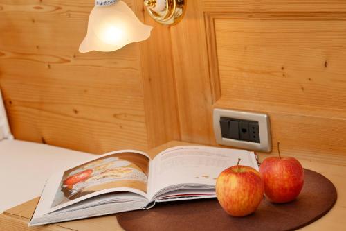 an open book on a table with two apples at Hotel Hubertusstube in Laion