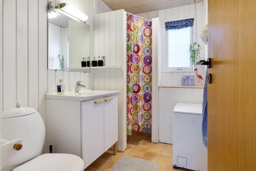 a white bathroom with a toilet and a sink at Scenic Summer House On Langeland in Humble