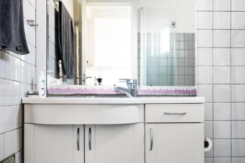 a white bathroom with a sink and a mirror at Bornholm Holiday Apartment With Sea View in Allinge