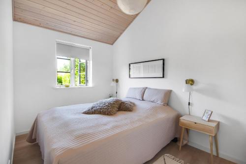 a white bedroom with a bed and a window at New Modern Holiday Home Near The Beach And City in Nykøbing Sjælland