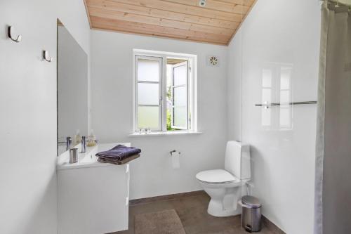 a white bathroom with a toilet and a window at New Modern Holiday Home Near The Beach And City in Nykøbing Sjælland