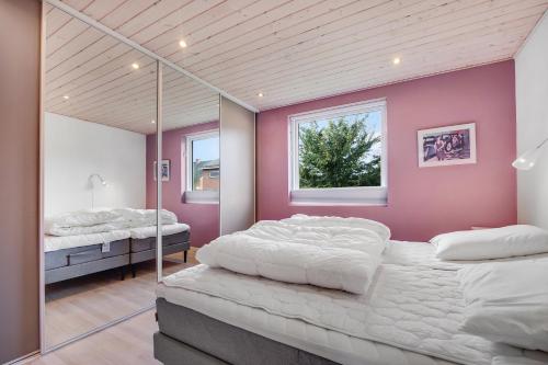 two beds in a room with pink walls and mirrors at Cozy And Spacious Townhouse In Aars in Års