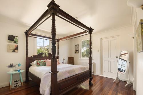 a bedroom with a four poster bed and a window at Hillside Cottage Berrima in Berrima