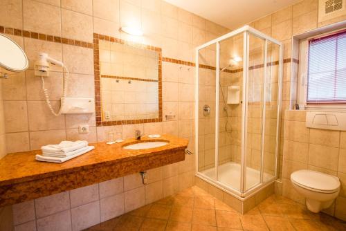 a bathroom with a sink and a shower and a toilet at Hotel Grundlhof in Bramberg am Wildkogel