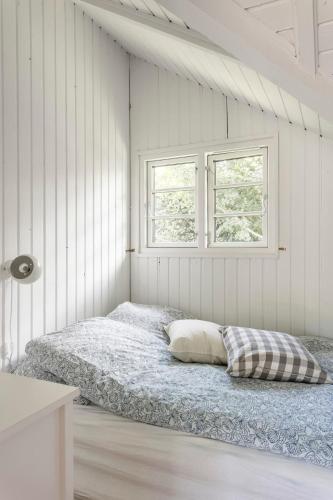 a bed in a white room with two windows at Idyllic Summer House Close To Beach And Forest in Tisvildeleje
