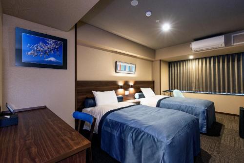 a hotel room with two beds and a table at Tenseien Odawara Station Annex in Odawara