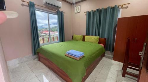 a small bedroom with a green bed with a window at khounxub view hotel in Ban Pho Touane