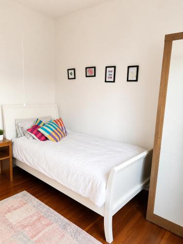 a white bed in a room with pictures on the wall at Farm Stay | Near Airport & Mystery Creek in Tamahere