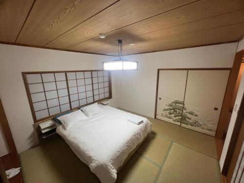 a bedroom with a white bed in a room at Momo Lodge Madarao in Iiyama
