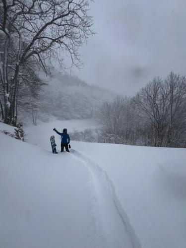 a person standing on a snowboard on a snow covered slope at Momo Lodge Madarao in Iiyama