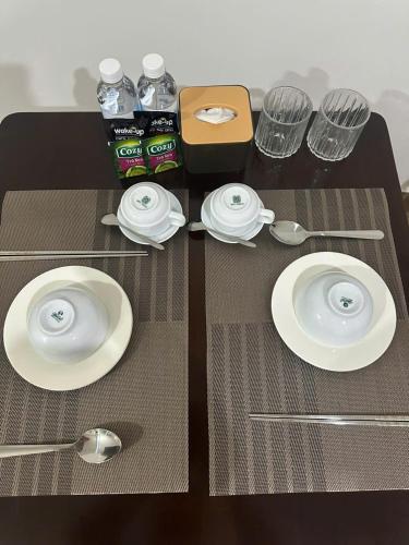 a table with plates and spoons and bottles of water at Full House Hotel Apartment in Danang