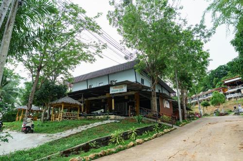a building on the side of a street with trees at Green Gen Hotel Phuket in Phuket