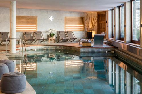 a swimming pool with chairs in a house at Hotel Hermitage Relais & Châteaux in Breuil-Cervinia