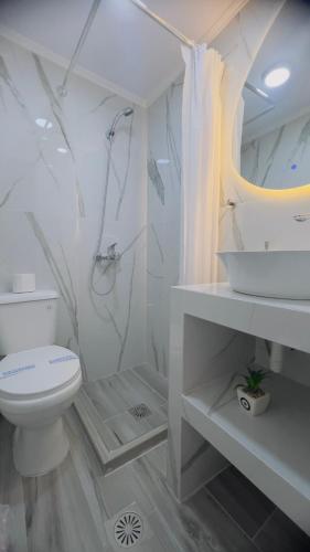a white bathroom with a toilet and a sink at Hotel Trifylia in Kyparissia
