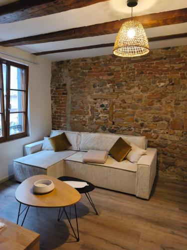 a living room with a couch and a brick wall at Logis Saint Martin in Colmar