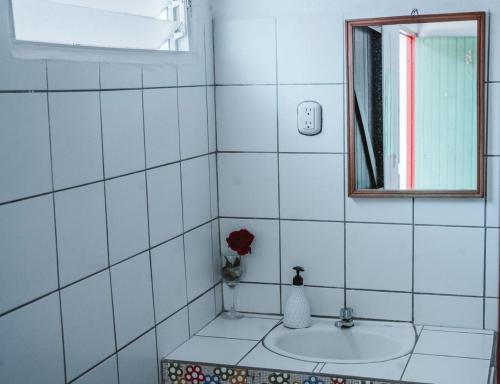 a white tiled bathroom with a sink and a mirror at Hostal Vacaciones Nicas in León