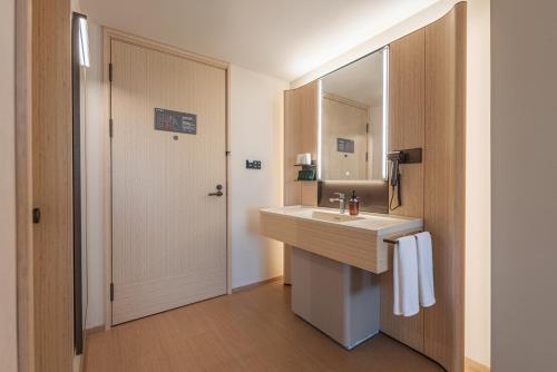 a bathroom with a sink and a mirror at Zhangjiajie JI Hotel- New hotel, Free pick up service, Free shuttle service for Tianmen Mount Cableway, Smart Hotel&Root Service,King Koil mattress, Free self-service laundry,Toursim Service&English Customer Service in Zhangjiajie