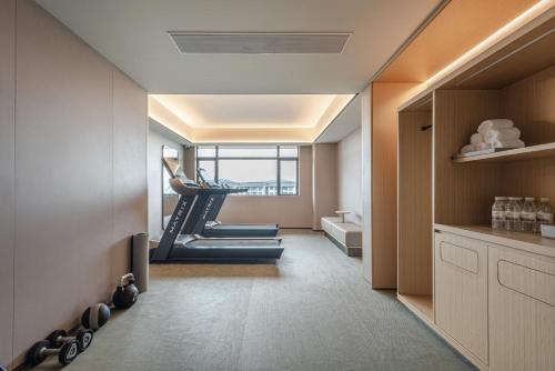 a room with a gym with a woman on a treadmill at Zhangjiajie JI Hotel- New hotel, Free pick up service, Free shuttle service for Tianmen Mount Cableway, Smart Hotel&Root Service,King Koil mattress, Free self-service laundry,Toursim Service&English Customer Service in Zhangjiajie
