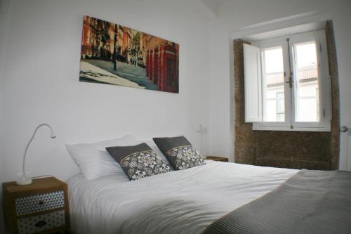 a white bed with pillows and a picture on the wall at Apartamentos Pombal in Santiago de Compostela