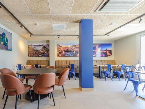 a waiting room with tables and chairs and paintings on the walls at Ibis Budget La Rochelle Puilboreau in Puilboreau