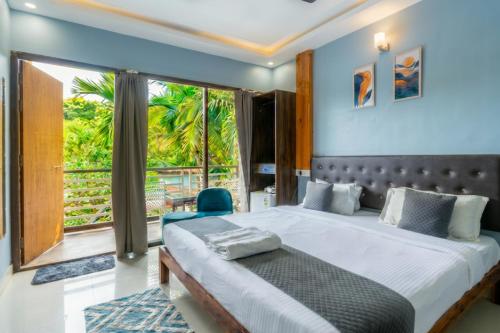 a bedroom with a large bed and a large window at YogiTree Beach Resort & Cafe - 100m from Morjim Beach in Morjim