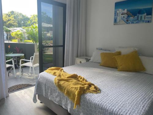 a bedroom with a bed with a yellow blanket on it at Eden on Beach in Palm Cove