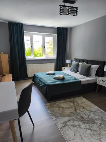 a bedroom with a bed and a table and window at Lyra Apartment 2 in Sfântu-Gheorghe